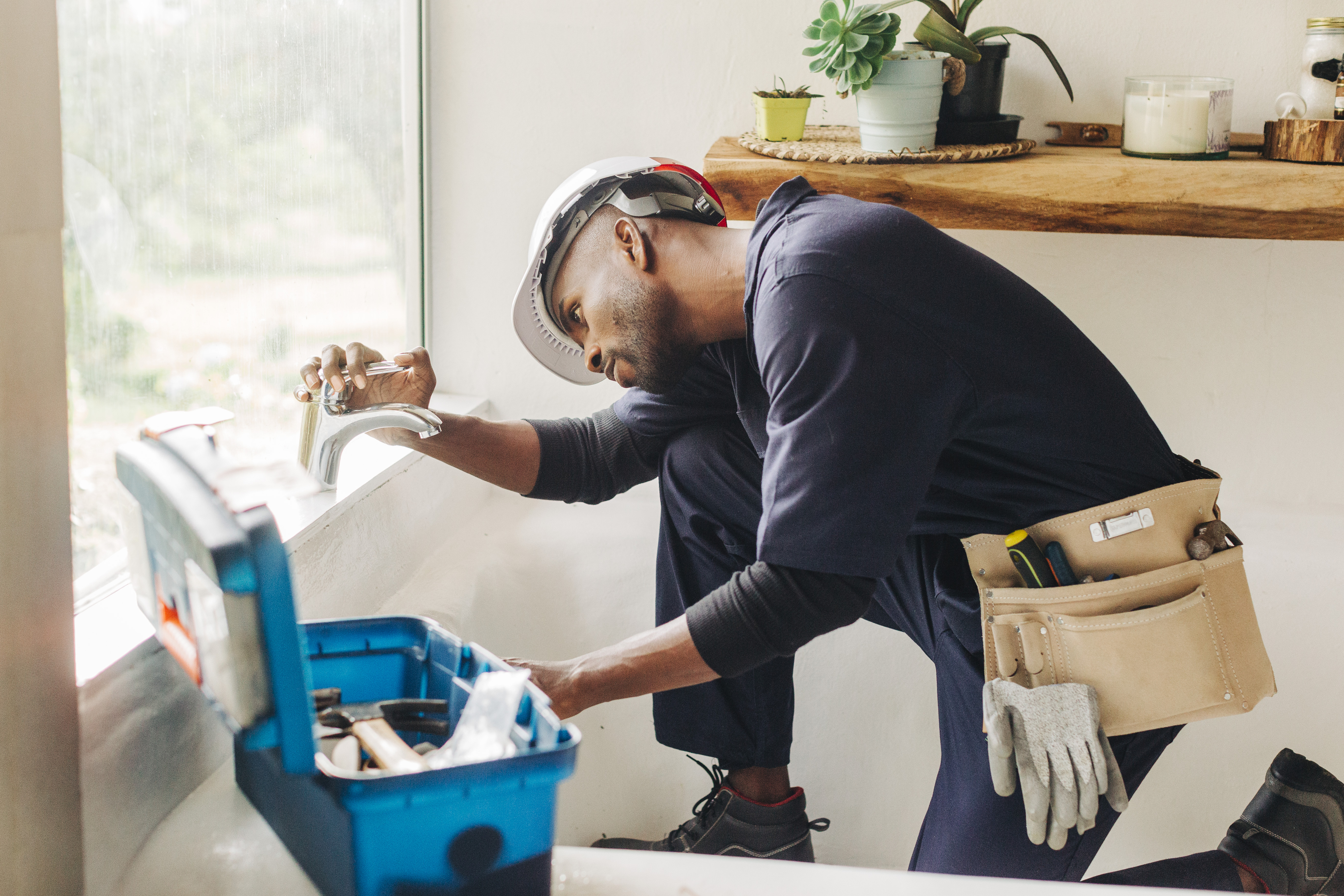 Plumber working on a bath faucet in a home