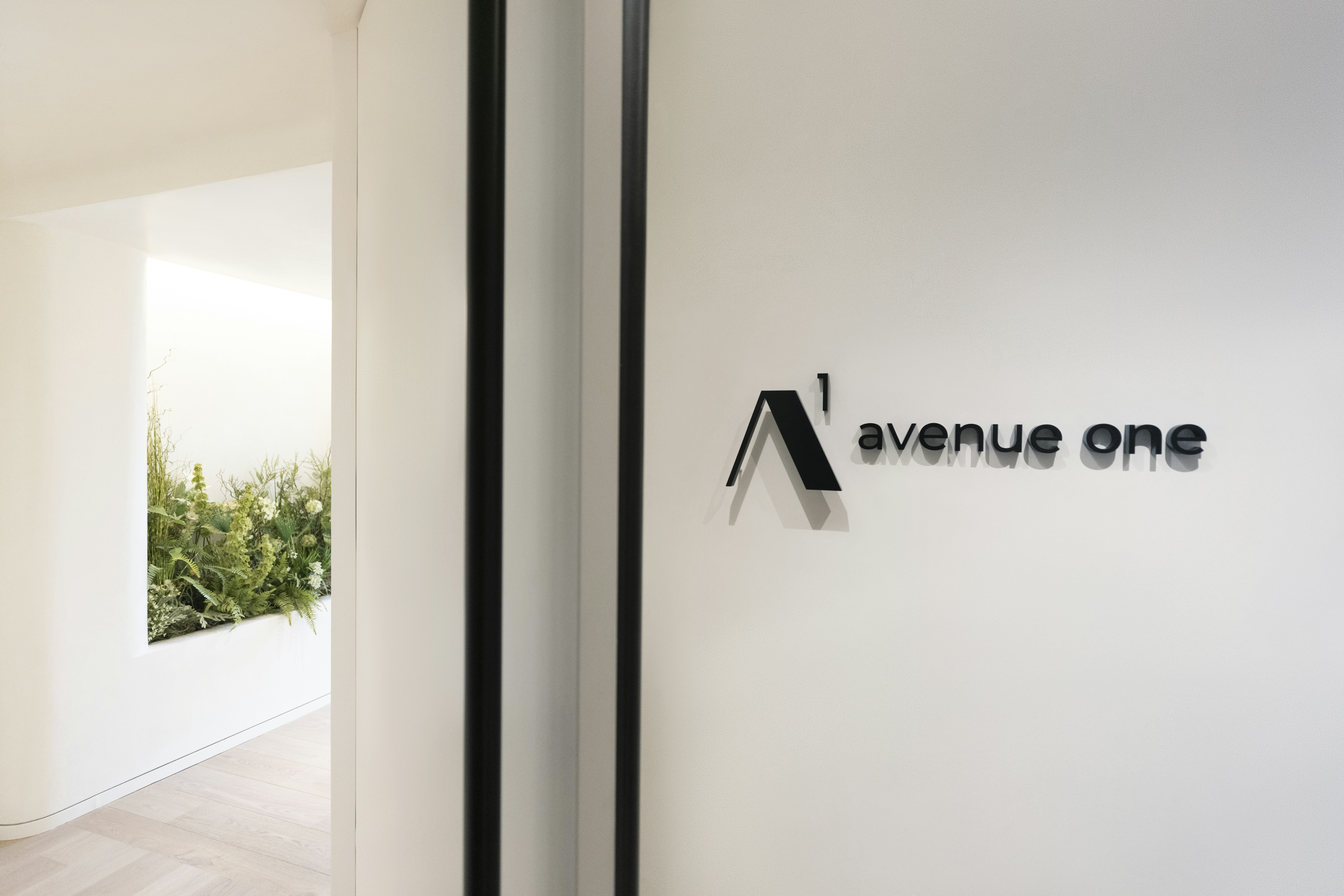 Photo of the the entrance to the avenue one office. White door with the avenue one logo on the connecting wall