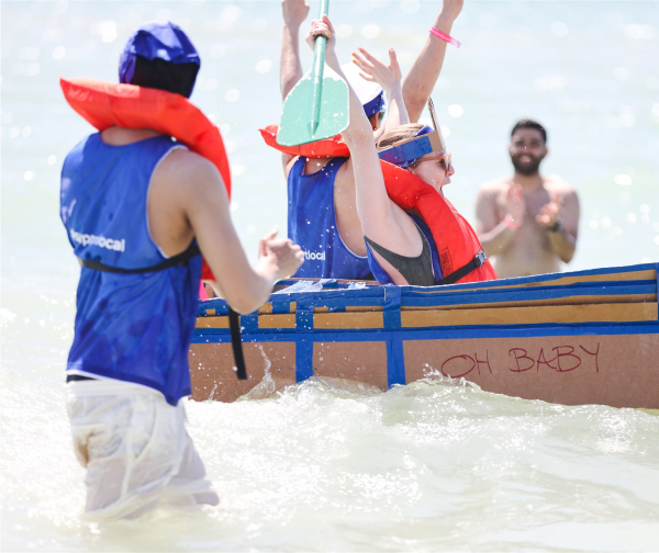 Group of people in the ocean in a cardboard boat celebrating
